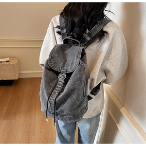Gros plan du sac à dos en denim délavé avec boucles métalliques et fermeture à cordon