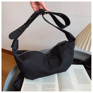 Detail of black crescent shoulder bag featuring ruched fabric and silver zipper