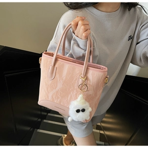 Détail d'un sac cabas plissé rose avec breloque peluche et doubles poignées