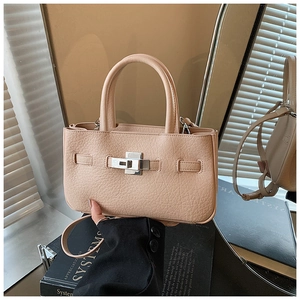 Detail of apricot lychee pattern leather handbag featuring silver twist lock and strap