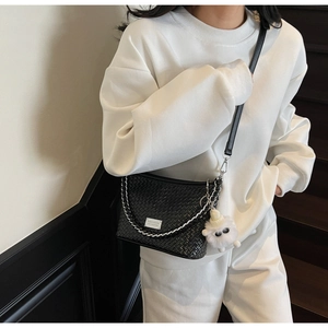 Detail of black woven crossbody bag with silver chain and cute plush sheep charm