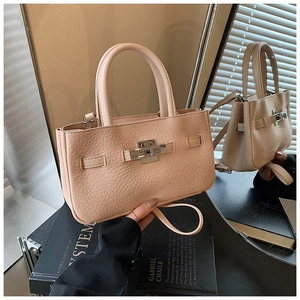 Detail of a beige lychee grain leather handbag with metal turn-lock and detachable strap