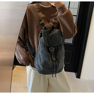 Détail du sac à dos en jean noir délavé avec boucle métallique et cordon de serrage