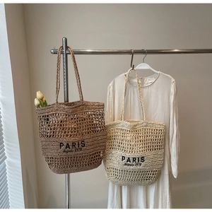 Detalle de bolsos tote de paja calada en marrón y beige con bordado de París