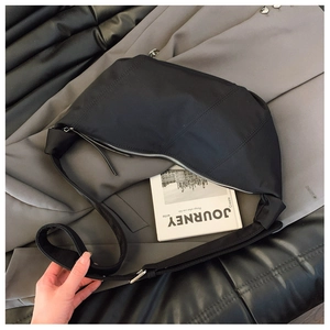 Detail of black nylon crescent bag showing knotted shoulder strap and silver zipper hardware