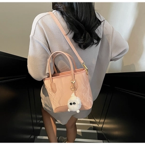 Détail d'un sac à main rose texture marbre avec charm peluche blanche et bandoulière