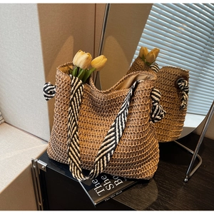 Détail du sac cabas en paille tissé avec bandoulière rayée et décor floral à l'intérieur