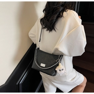 Detail of black woven shoulder bag with silver chain and cute white sheep charm pendant