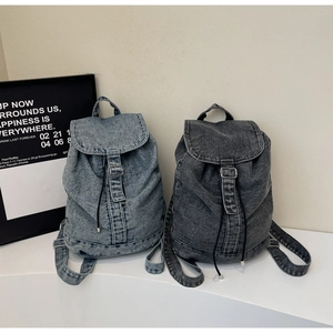 Détail d'un sac à dos en denim avec rabat, cordon de serrage et sangles de bouclage en cuir