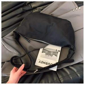 Detail of black nylon hobo bag with silver zipper, wide strap and spacious interior