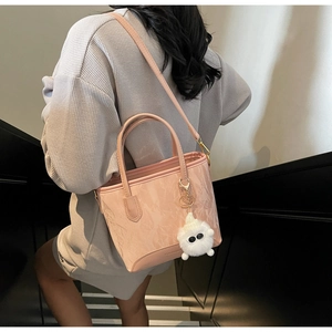 Détail d'un sac cabas rose clair plissé avec charm en peluche blanche sur un mannequin