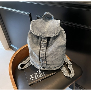 Détail d'un sac à dos en denim bleu clair avec boucle en métal et cordon de serrage