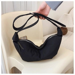 Detail of a black pleated nylon dumpling bag showing its glossy finish and knotted strap