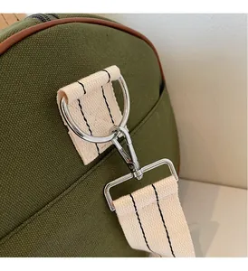 Close-up of green canvas travel bag featuring silver metal D-ring and striped woven strap