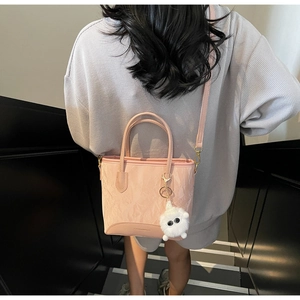 Détail d'un sac à main plissé rose avec bandoulière réglable et pendentif en peluche