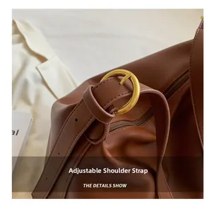 Detail view of adjustable leather shoulder strap with a polished golden metal buckle