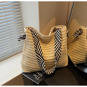 Détail d'un sac cabas en paille tissée avec des anses en tissu rayé noir et blanc