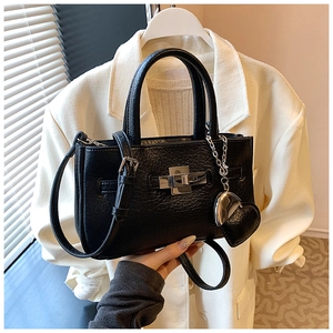 Detail of black textured bucket bag with silver twist lock and heart pendant charm