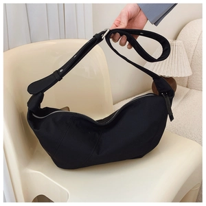 Detail view of the black pleated crescent bag with adjustable strap and silver zipper closure