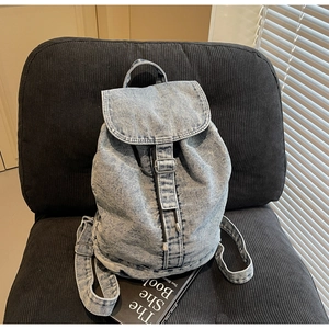 Détail d'un sac à dos en denim bleu clair avec boucle métallique et cordon de serrage