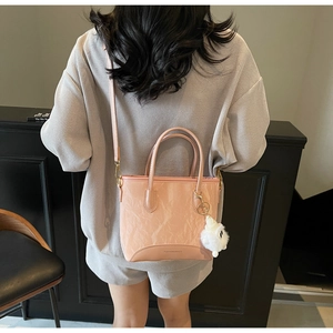 Sac bandoulière rose plissé avec breloque ours porté à l'épaule par un mannequin
