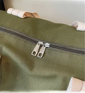 Detailed macro view of olive green canvas bag showing durable silver metal dual zippers