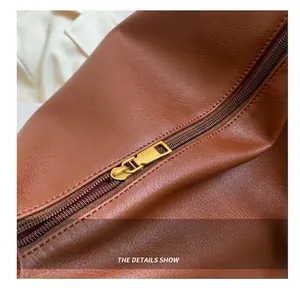 Detail view of smooth golden metal zipper and brown lychee grain leather on tote bag