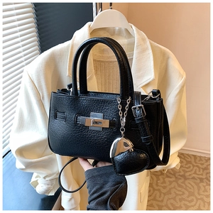 Detail of black textured bucket bag with silver twist lock and heart pendant