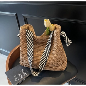 Détail du sac cabas en paille avec bandoulière chevron noir et blanc sur chaise