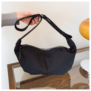 Close-up of black crescent nylon shoulder bag with adjustable strap and silver zipper detail