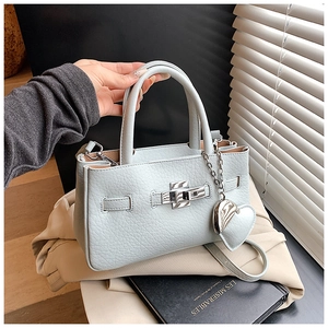 Detail of light blue lychee pattern handbag with silver heart charm and cross-body strap