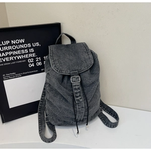 Détail du sac à dos en jean gris avec fermeture à cordon et rabat à boucle métallique