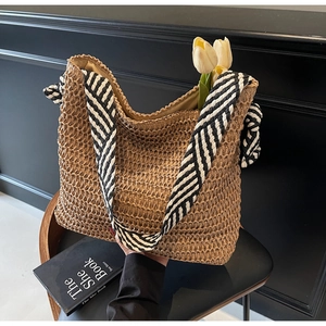 Détail du cabas en paille tissée avec bandoulière textile chic à rayures noir et blanc