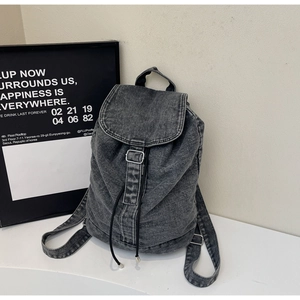 Détail du sac à dos en jean gris avec rabat, boucles métalliques et cordon de serrage