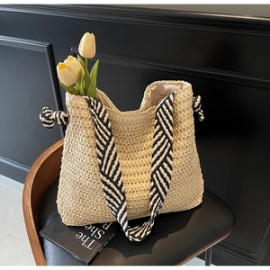Détail du sac seau en paille beige avec bandoulière tissée à rayures noir et blanc