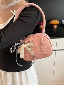 Borsa rosa in pelle martellata con fiocco in pizzo indossata a spalla da una modella