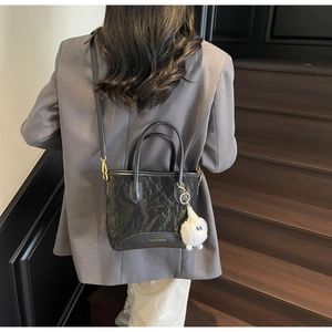 Détail du sac seau noir plissé avec logo doré et charm monstre en peluche blanche