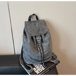 Gros plan d'un sac à dos en denim gris vintage avec cordon de serrage et boucle en métal