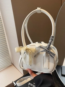 Piccola borsa a mano bianca in pelle con manici ad arco e fiocchi decorativi
