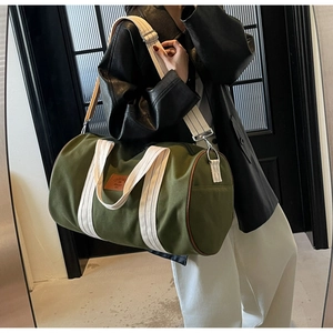 Olive green canvas duffel bag with leather patch detail and wide shoulder strap