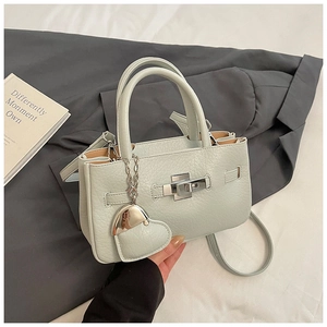 Detail view of mint green pebble leather handbag with silver clasp and heart charm