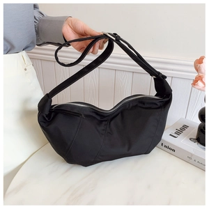 Detail of black nylon crescent bag featuring curved quilting and adjustable wide strap