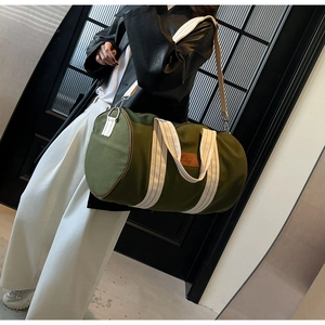 Detailed view of the army green canvas travel duffle bag with a brown leather patch