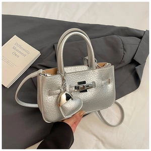 Detail of silver metallic bucket bag with cracked texture, lock closure and heart charm