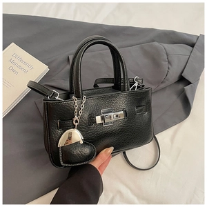 Detailed view of black bucket bag with lychee grain texture and heart chain charm