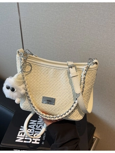 Chic cream woven underarm bag with silver chain strap and plush monster charm