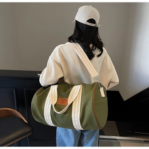 Detail of army green travel bag with striped handles carried on a model's shoulder