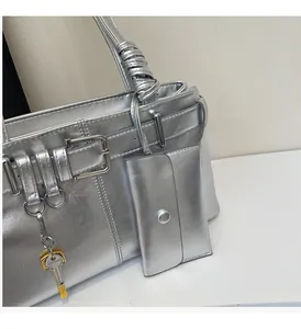 Detail of silver metallic tote bag with buckle strap and small hanging accessory pouch