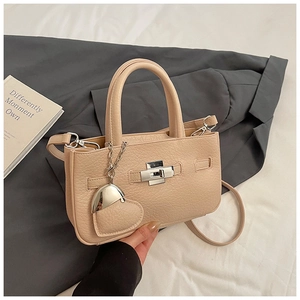 Detail of apricot bucket bag with lychee texture, silver twist lock and heart charm
