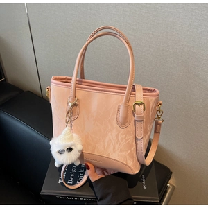 Vue détaillée du sac cabas plissé rose avec pendentif peluche sur des livres